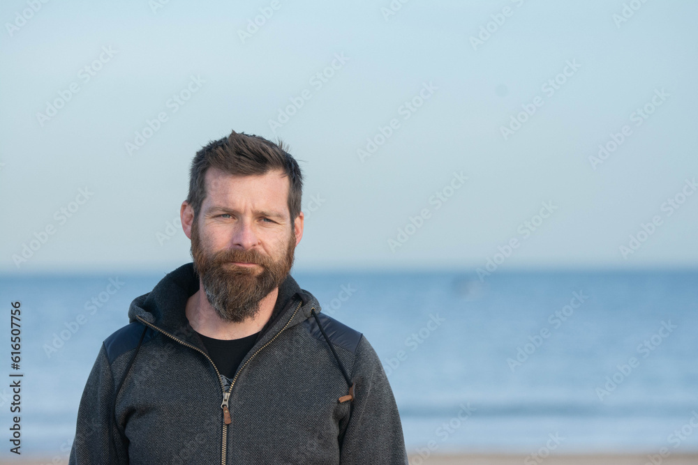 Portrait of man standing on sandy beach. bearded man at beach