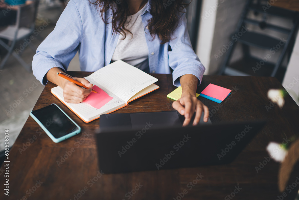 Obraz premium Woman with laptop taking notes in planner
