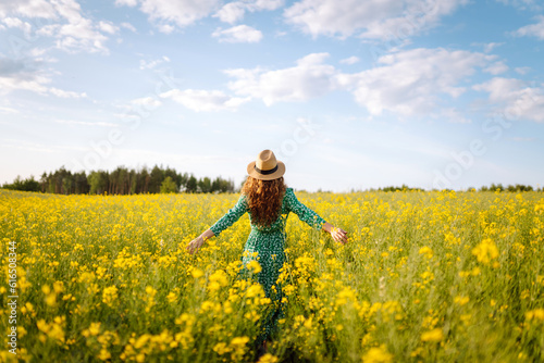Young woman walking flowering field gently touch yellow flowers. Nature, vacation, relax and lifestyle. Summer landscape.