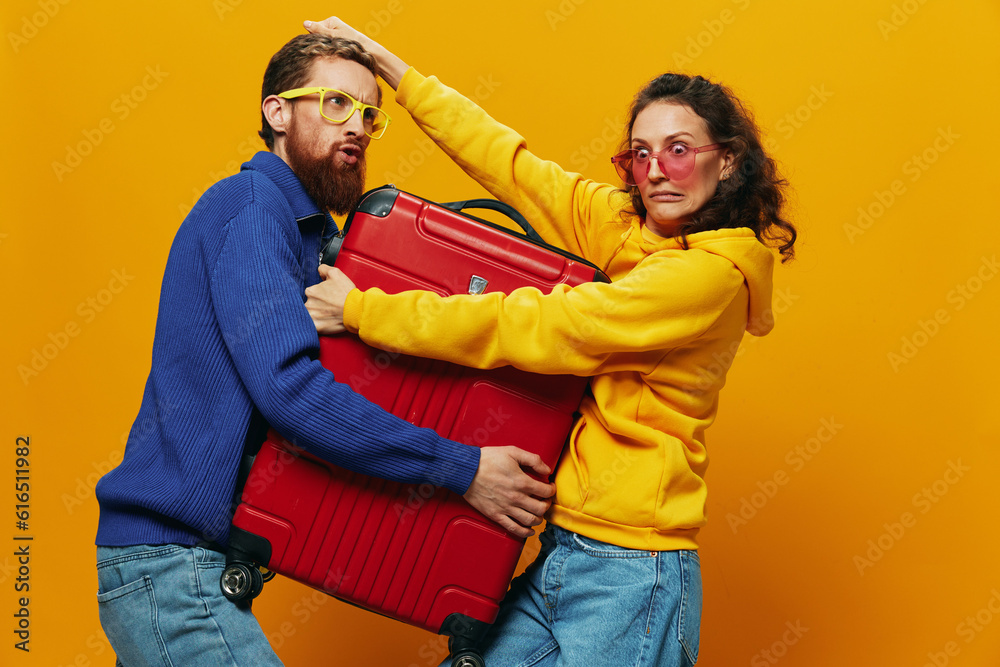 Obraz premium Woman and man smiling, suitcases in hand with yellow and red suitcase smiling merrily and crooked, yellow background, going on a trip, family vacation trip, newlyweds.