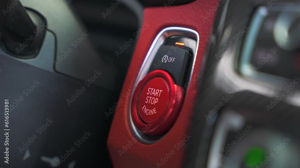 Man finger presses the red push start button in a sports car. Drive your dream vehicle on the high speed by the road