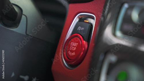 Man finger presses the red push start button in a sports car. Drive your dream vehicle on the high speed by the road