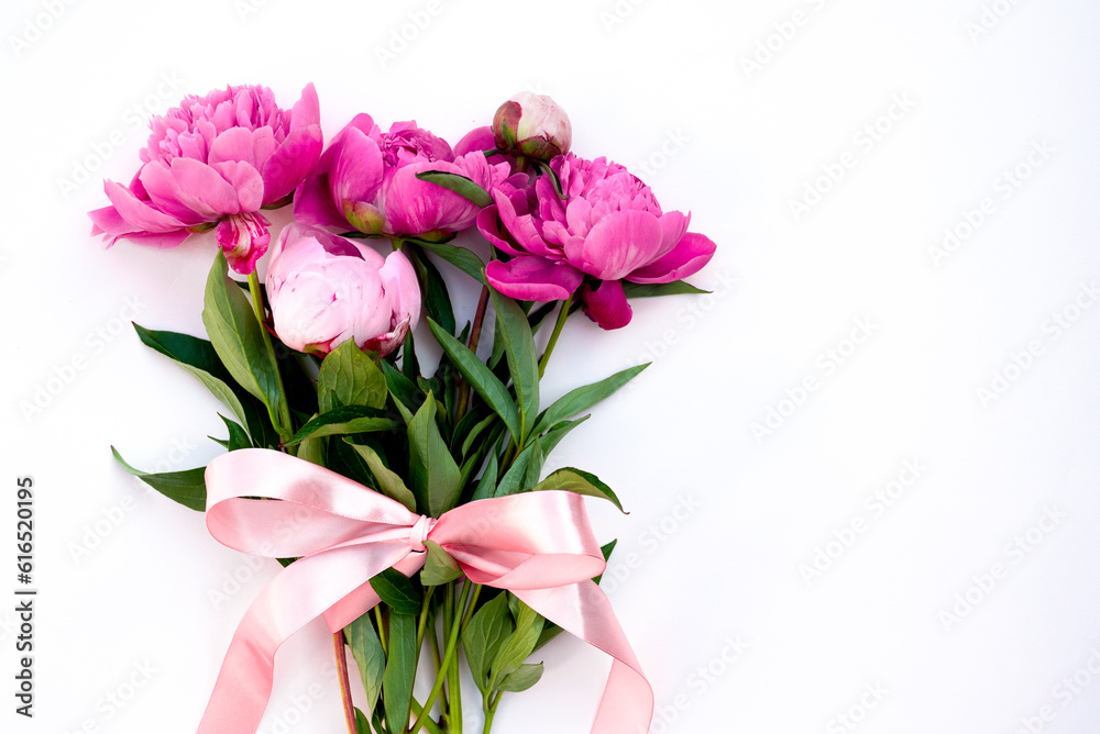 Bouquet of pink Peonies tied with a pink bow. Spring flowers on the white background. Flower arrangement of pink peonies and place for text. Flower bouquet, lat lay. Pink flowers with a ribbon. Bouquet of pink Peonies tied with a pink bow. Spring flowers on the white background. Flower arrangement of pink peonies and place for text. Flower bouquet, lat lay. Pink flowers with a ribbon.