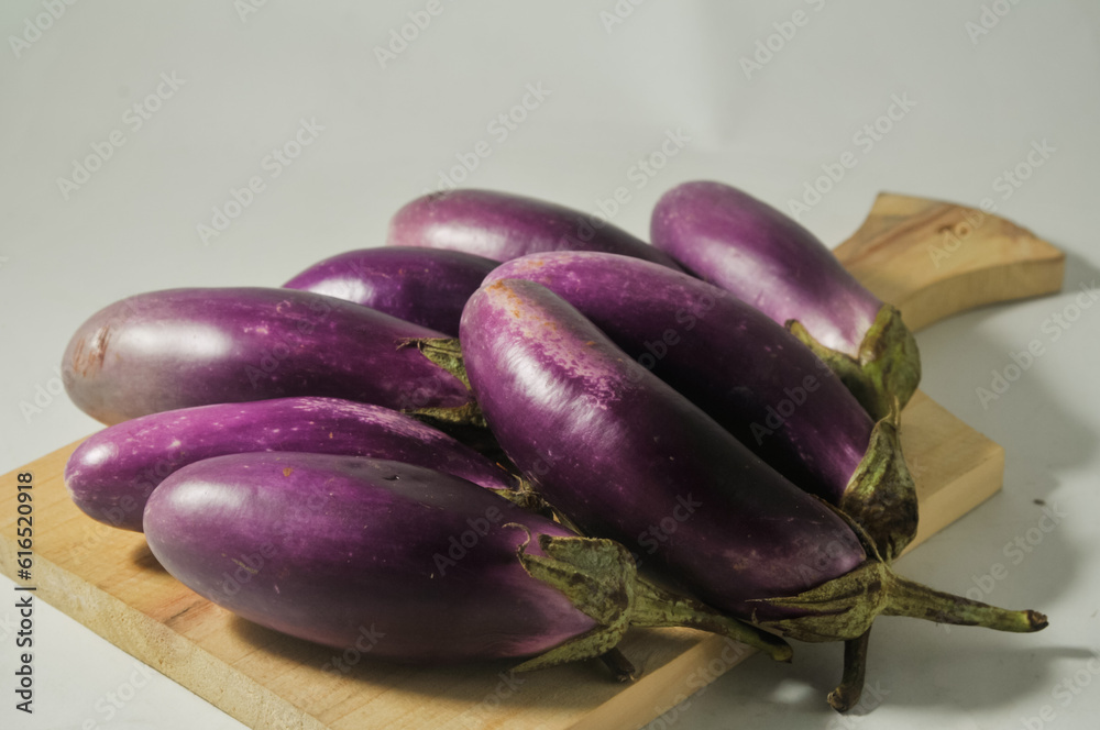 Some purple eggplant fruits on a wooden cutting board isolated on white background. Selected focus Some purple eggplant fruits on a wooden cutting board isolated on white background. Selected focus