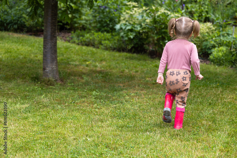 toddler girl spend time outdoor in rubber boots, children have fun in nature toddler girl spend time outdoor in rubber boots, children have fun in nature