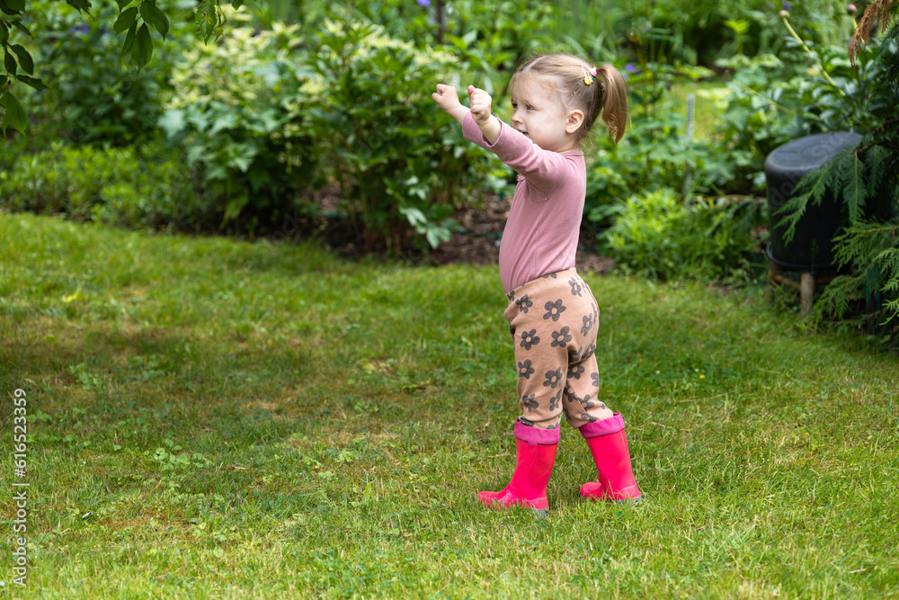 toddler girl spend time outdoor in rubber boots, children have fun in nature
