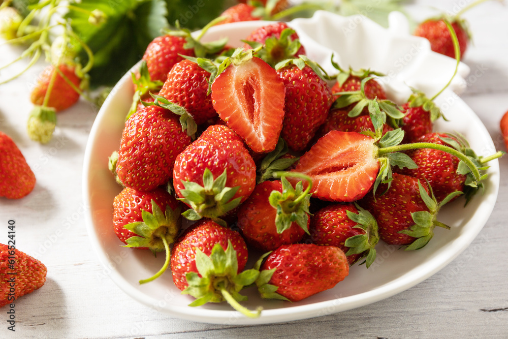 Harvest background. Organic farmer's market. Bowl of ripe freshly picked red strawberries on a white rustic table.