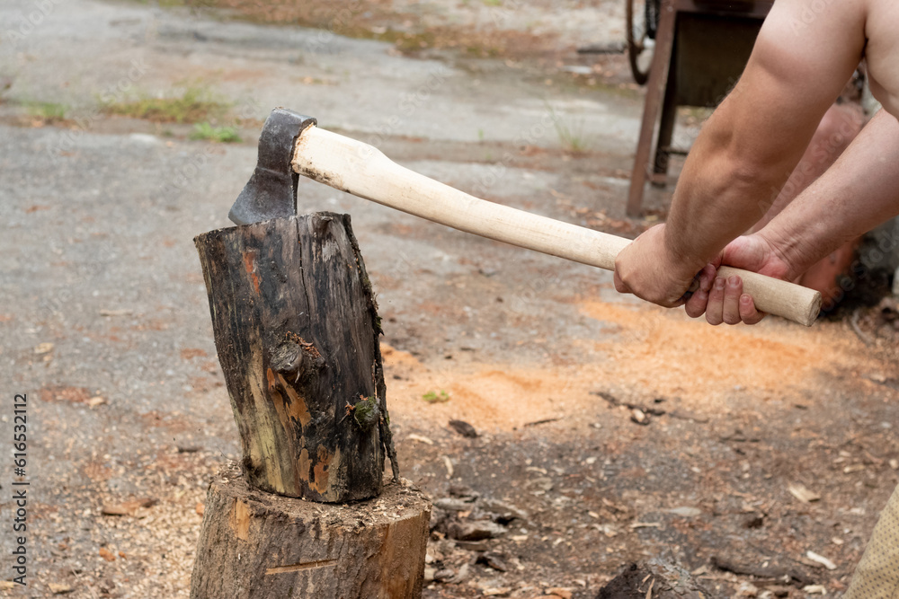 A man chops firewood with a large axe in the summertime A man chops firewood with a large axe in the summertime