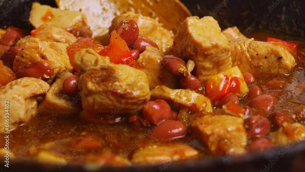 Spiced chicken with sumac and cholent beans is mixed with a wooden spatula Spiced chicken with sumac and cholent beans is mixed with a wooden spatula
