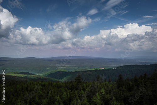 A view to Snieznik massif from a lookout tower on mount Orlica, Orlickie Mountains, Poland. Dense forest, cloudy sky. © Kati Lenart