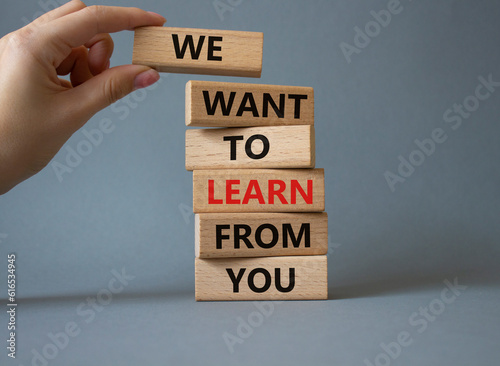 We want to learn from you symbol. Wooden blocks with words We want to learn from you. Beautiful grey background. Businessman hand. Business and We want to learn from you. Copy space.