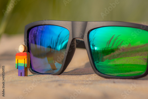 LGBT wooden people on the beach on the sand. Couple standing on beach with rainbow flag  equal rights  symbol of LGBT community. Sunglasses with LGBT flag on sandy beach. Summer travel concept.