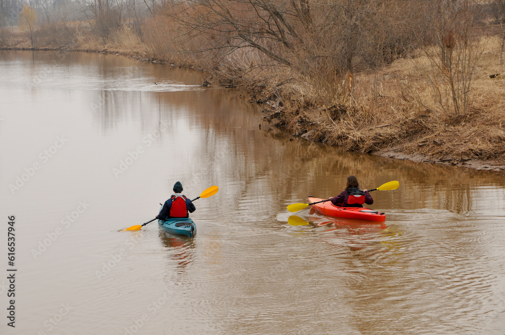 Kayakers On A Muddy River In Spring