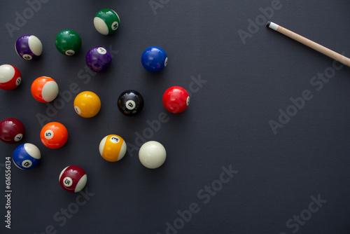 A top down view of a pool balls and a cue stick on a blue felt table. photo