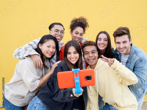 Group of diverse millennials recording a video or taking a photo for social media. Young people having fun with new technology 