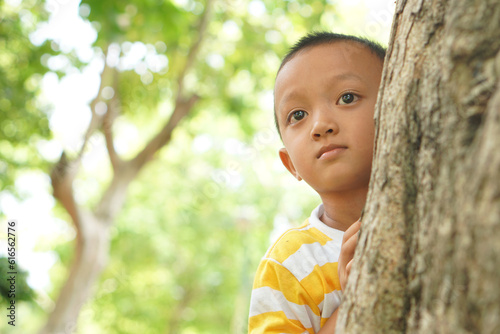 Photography Boy playing hide and seek in the garden