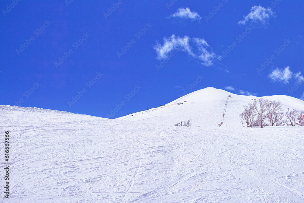 春スキーのニセコスキー場、綺麗な青空に映えるニセコアンヌプリ頂上とゲレンデ
