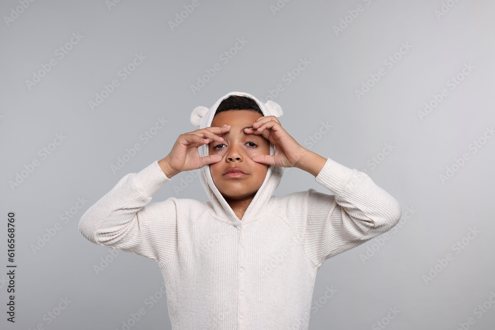 Sleepy boy in pajama on grey background. Insomnia problem