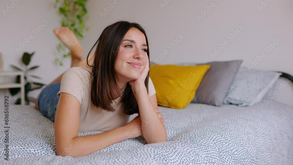 Young pretty woman relaxing lying on bed at home. Beautiful girl resting on bedroom looking at distance thinking. Home domestic lifestyle concept.