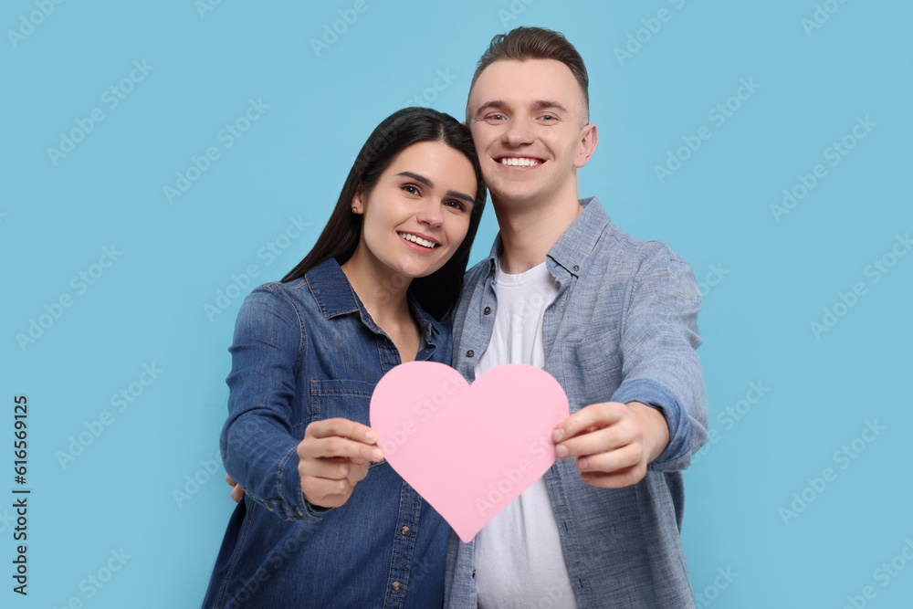 Lovely couple with decorative heart on light blue background. Valentine's day celebration