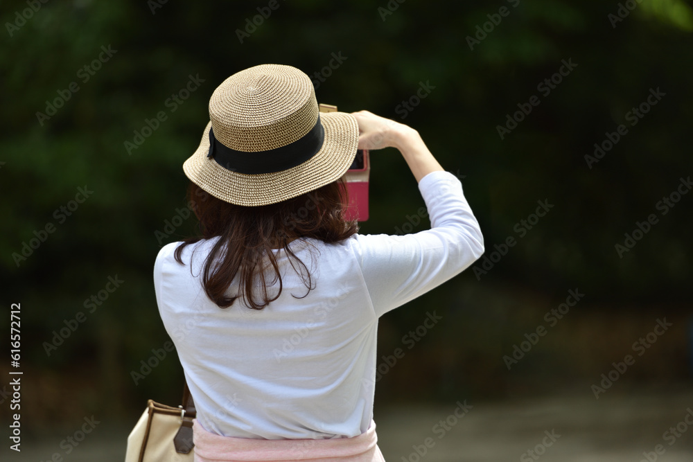 スマホで撮影する麦わら帽子の女性