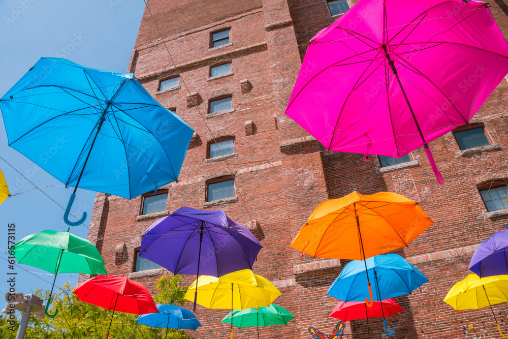 Beautiful colorful umbrellas against a deep blue sky and brick building.