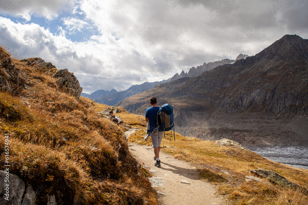 Hiker with a backpack on a mountain route in the Swiss Alps