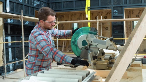 Building contractor worker using hand held worm drive circular saw to cut boards on a new home constructiion project photo