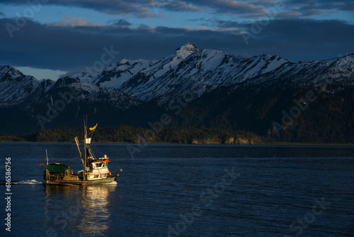 Fotografie Evening sun highlighting a fishing boat headed out to sea, Katchemak Bay just of