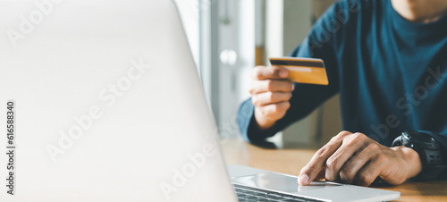 Man hand holding credit card and using laptop at home, Businessman or entrepreneur working, Online shopping, e-commerce, internet banking, spending money concept. photo