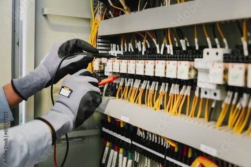 Foto Electrical engineers test electrical installations and wiring on protective relays, measuring them with a multimeter