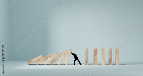 Silhouette of a man in panic against collapsing wooden dominos. Business crisis and failure concept in wide view.