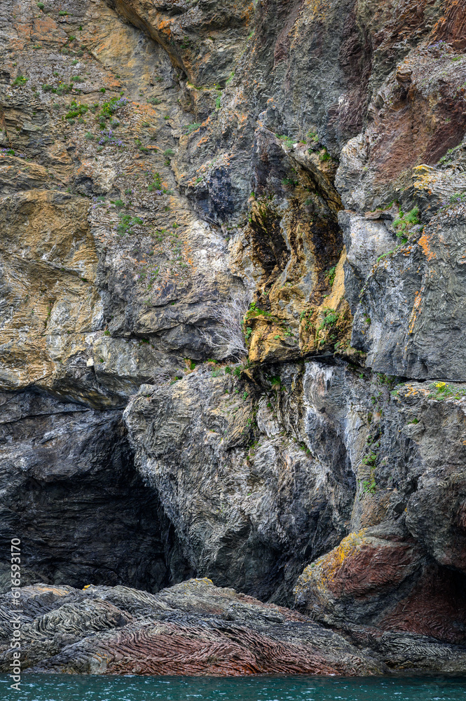 Fascinating geologic rock formation with a crying face on the cliff face, as a nature background, Katchemak Bay, AK
