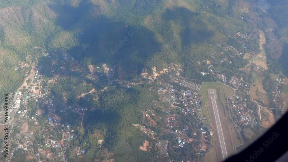 Top view small airport runway and local town on Thailand mountain hill area aerial plane window scene Top view small airport runway and local town on Thailand mountain hill area aerial plane window scene