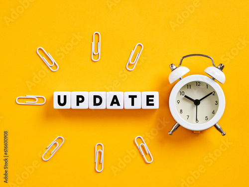 The word update on cubes with alarm clock and paper clips. Time for a software update. News update announcement.