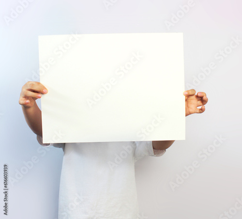 hands of a child holding in front of him a blank paper on a white background