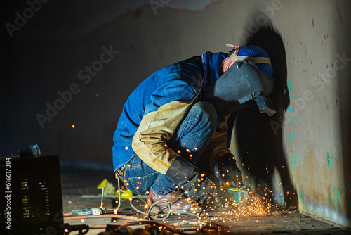 Male worker grinding on steel plate with flash of sparks close up wear protective gloves oil inside