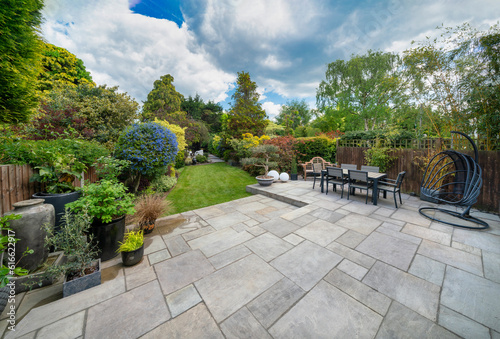 Beautiful summer garden in England, UK with lawn and large indian sandstone patio. photo