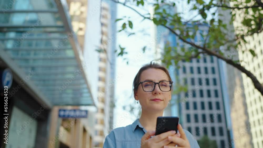 Caucasian woman in glasses walking around the city and using smartphone Caucasian woman in glasses walking around the city and using smartphone