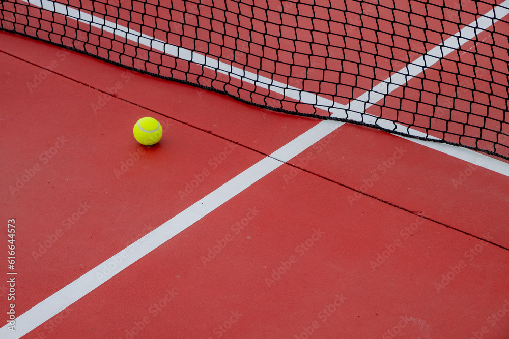 view of a ball near the net of a red tennis court