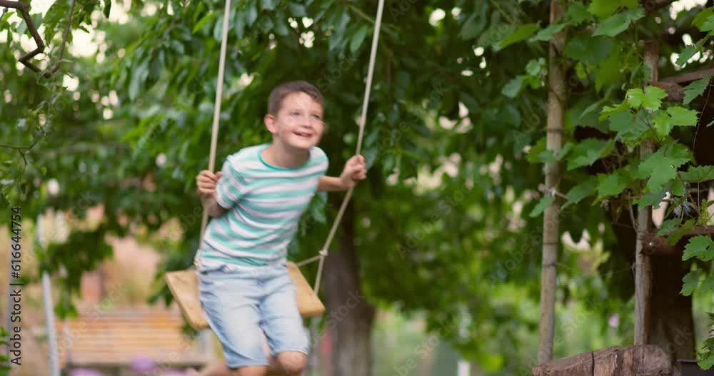 Happy little boy swinging on a swing in the garden. Happy little boy swinging on a swing in the garden.