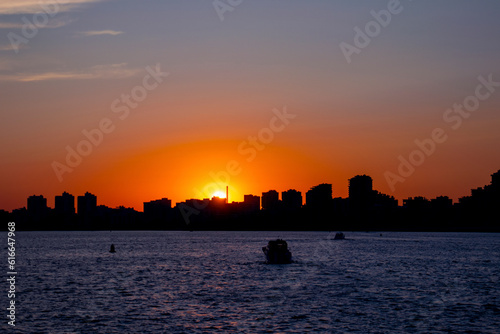 the silhouette of the city by the water at sunset © Наталья Удалова
