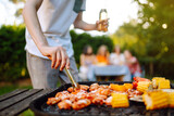 Assorted delicious grilled meat with barbecue grilled vegetables. Сompany of people gathered for barbecue in summer garden. Summer, party, adventure, youth, frienship concept