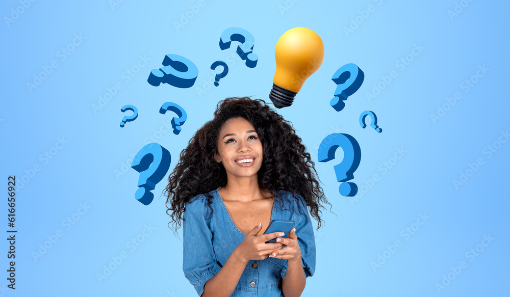 Fototapeta premium Cheerful African woman college student with phone, question marks and light bulb