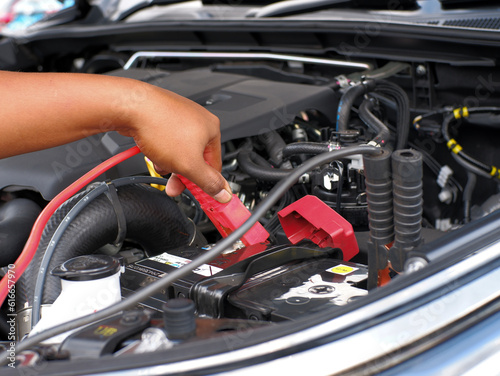 man charging car battery using jumper cables