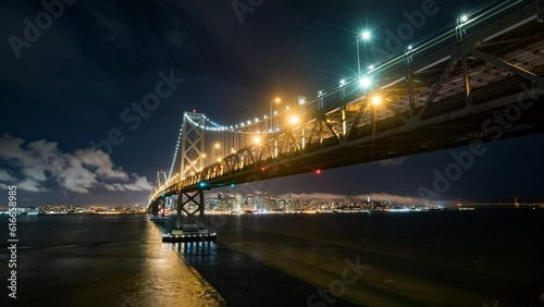 Lockdown Time Lapse Shot Of Illuminated Oakland Bay Bridge Over Sea Near City Against Sky At Night - San Francisco, California
