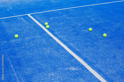 racket sports, five balls on the lines of a blue paddle tennis court © Vic