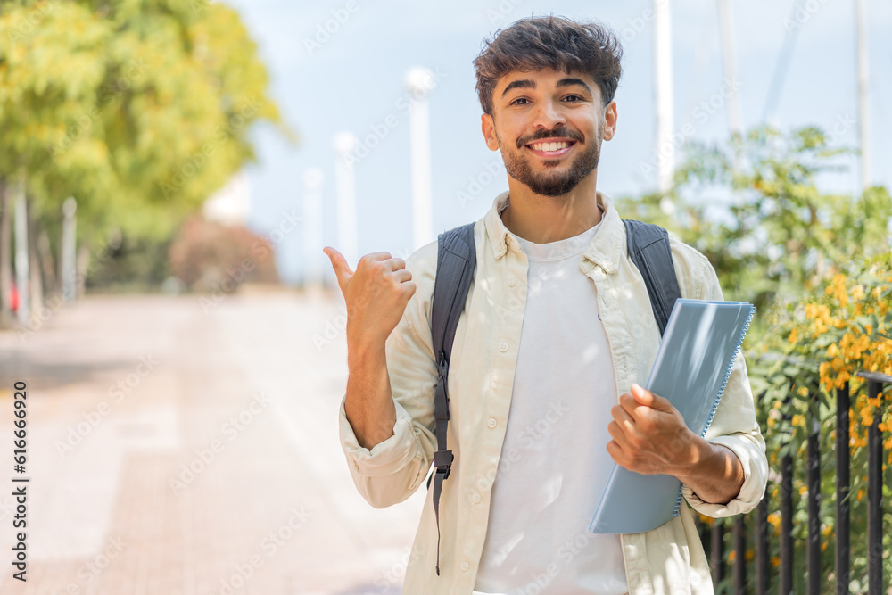 © luismolinero - Young student Arabian man at outdoors pointing to the side to present a product © luismolinero - Young student Arabian man at outdoors pointing to the side to present a product