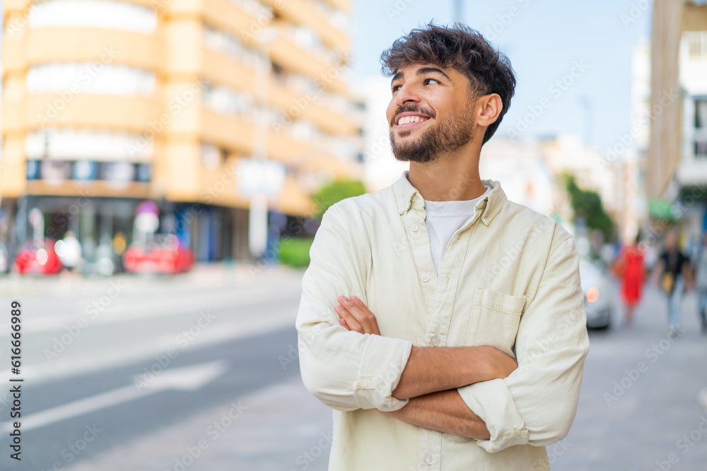 Young Arabian handsome man at outdoors looking up while smiling Young Arabian handsome man at outdoors looking up while smiling