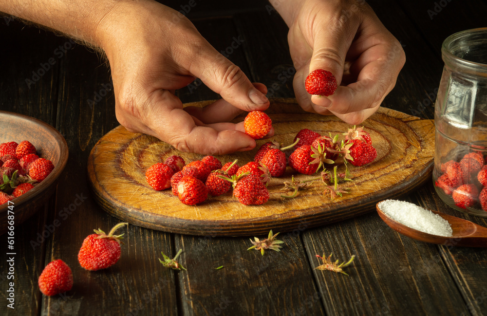 The chef prepares a sweet compote of fresh strawberries and sugar on the kitchen table. Canning strawberries in a jar
